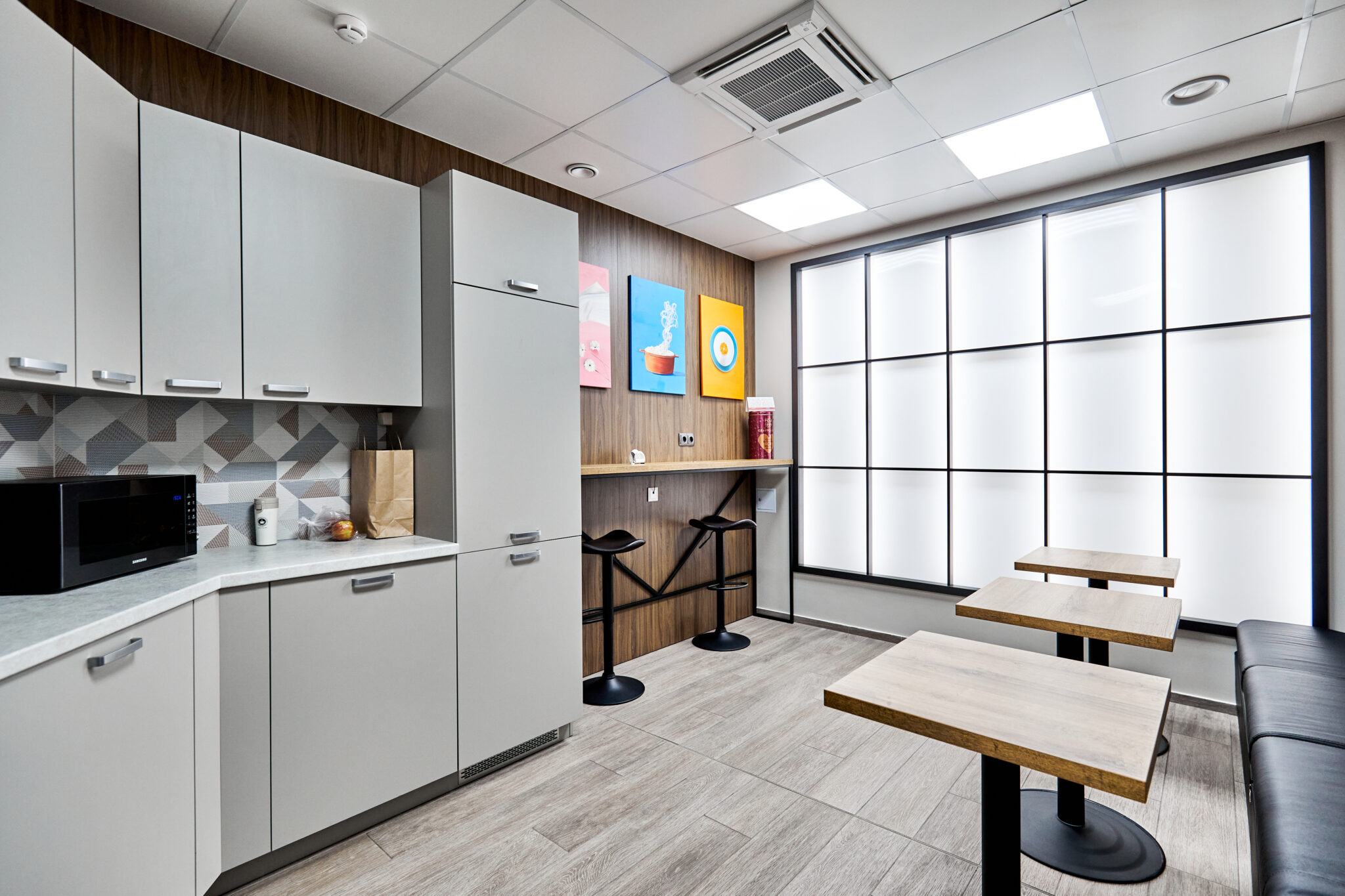 Kitchen in the office with small tables, bar stools, armchairs, microwave
